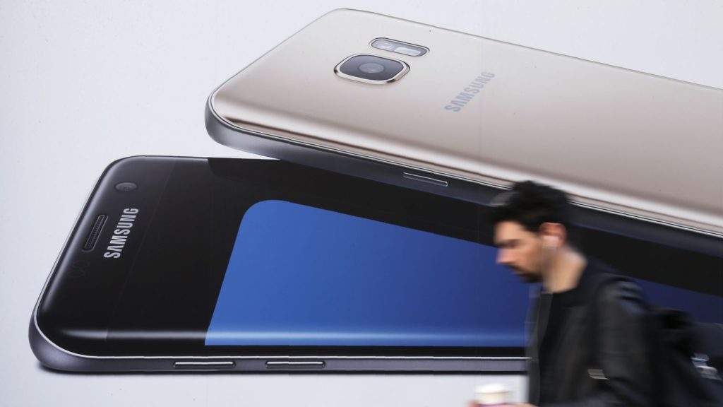 un homme utilise un smartphone alors qu il passe devant une publicite pour le samsung galaxy s7 a londres le 11 octobre 2016 5724161