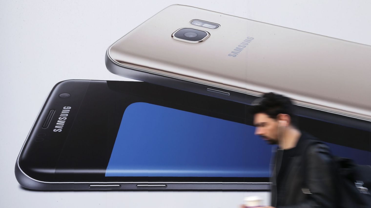 un homme utilise un smartphone alors qu il passe devant une publicite pour le samsung galaxy s7 a londres le 11 octobre 2016 5724161